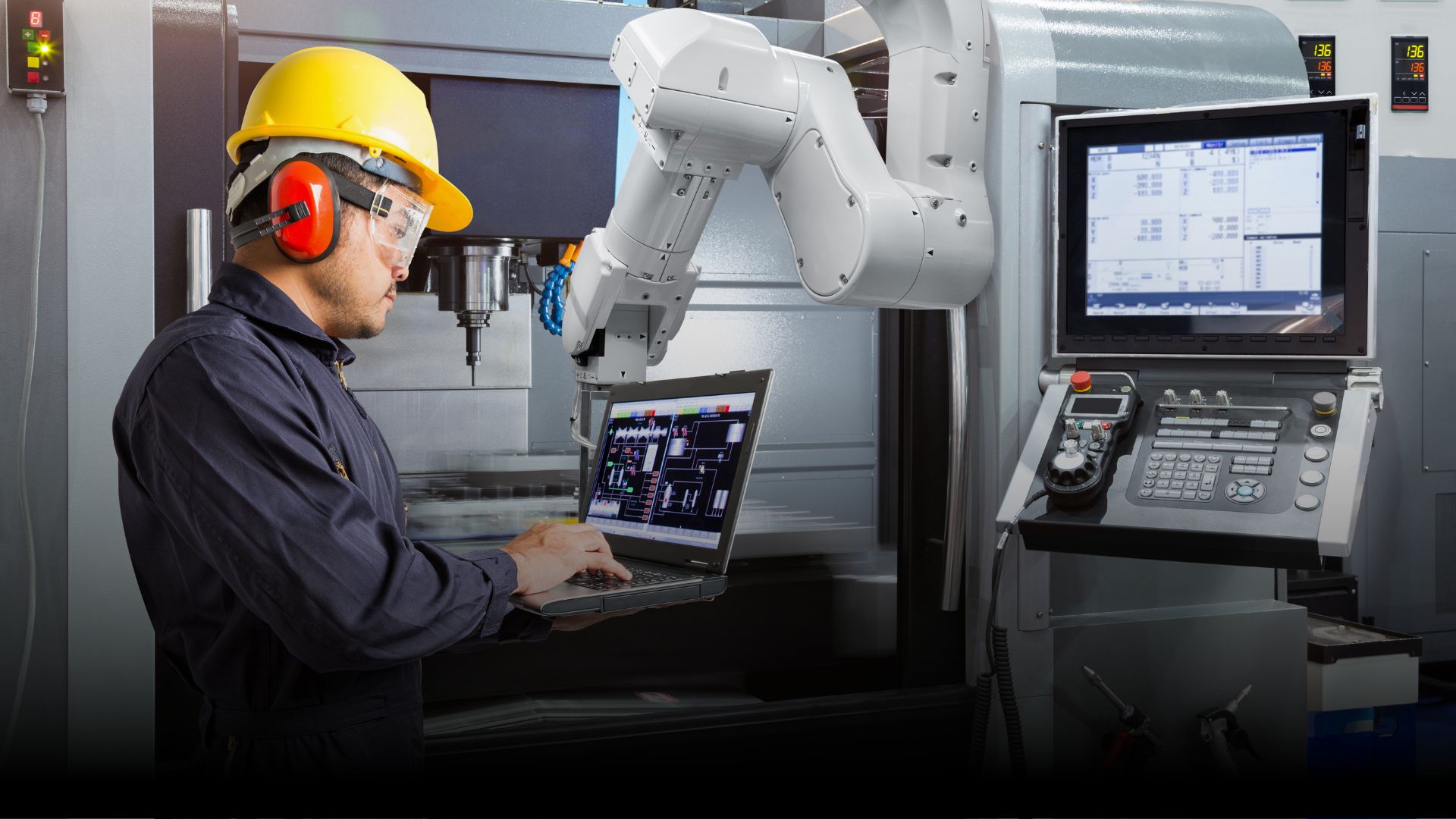 Operatore industriale davanti a robot e macchinario CNC per l'automatizzazione aziendale